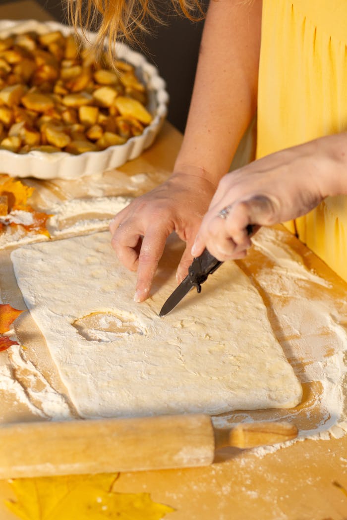 About Close-up of a woman making apple pie with dough and apples.